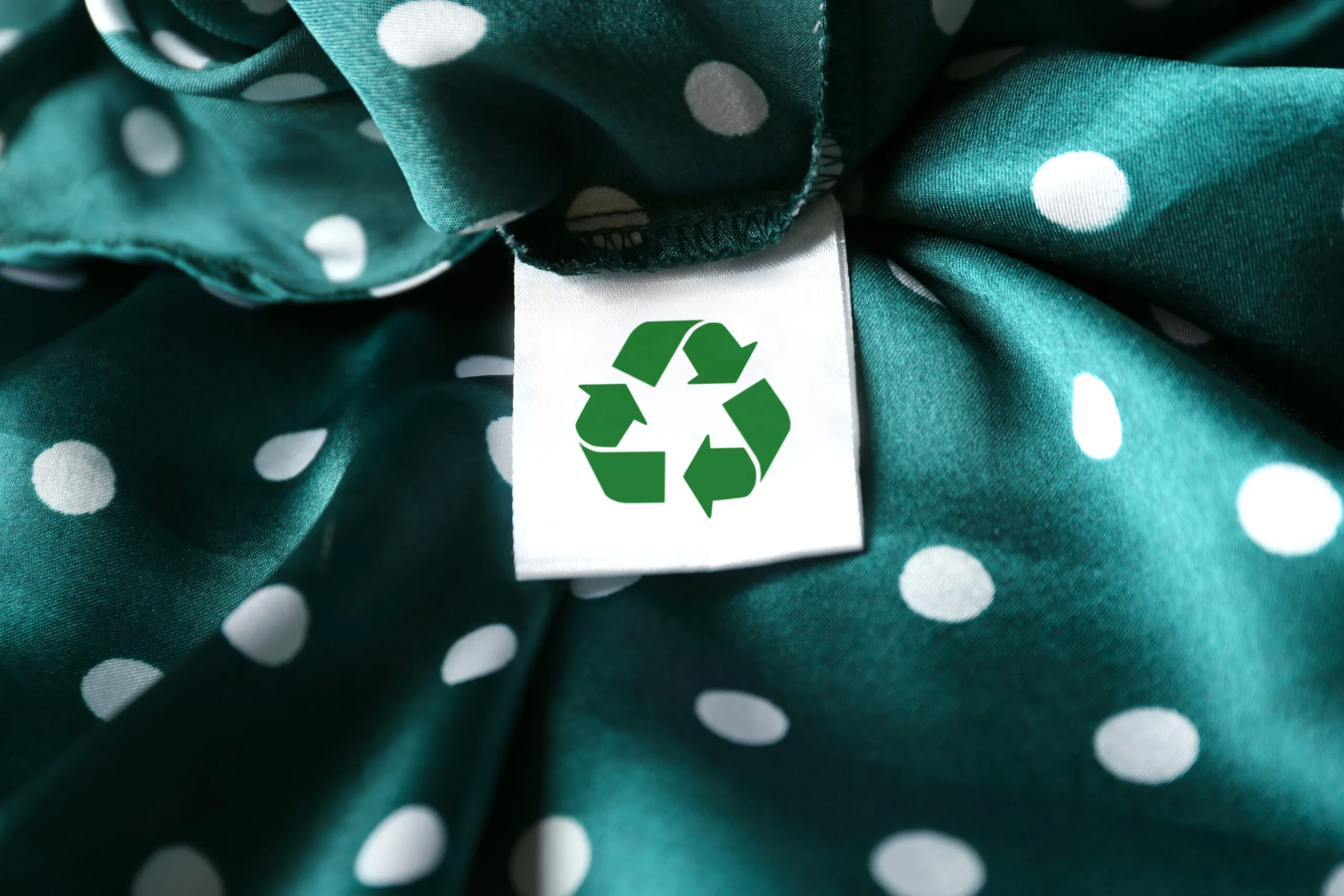 Clothing label with recycling symbol on green garment