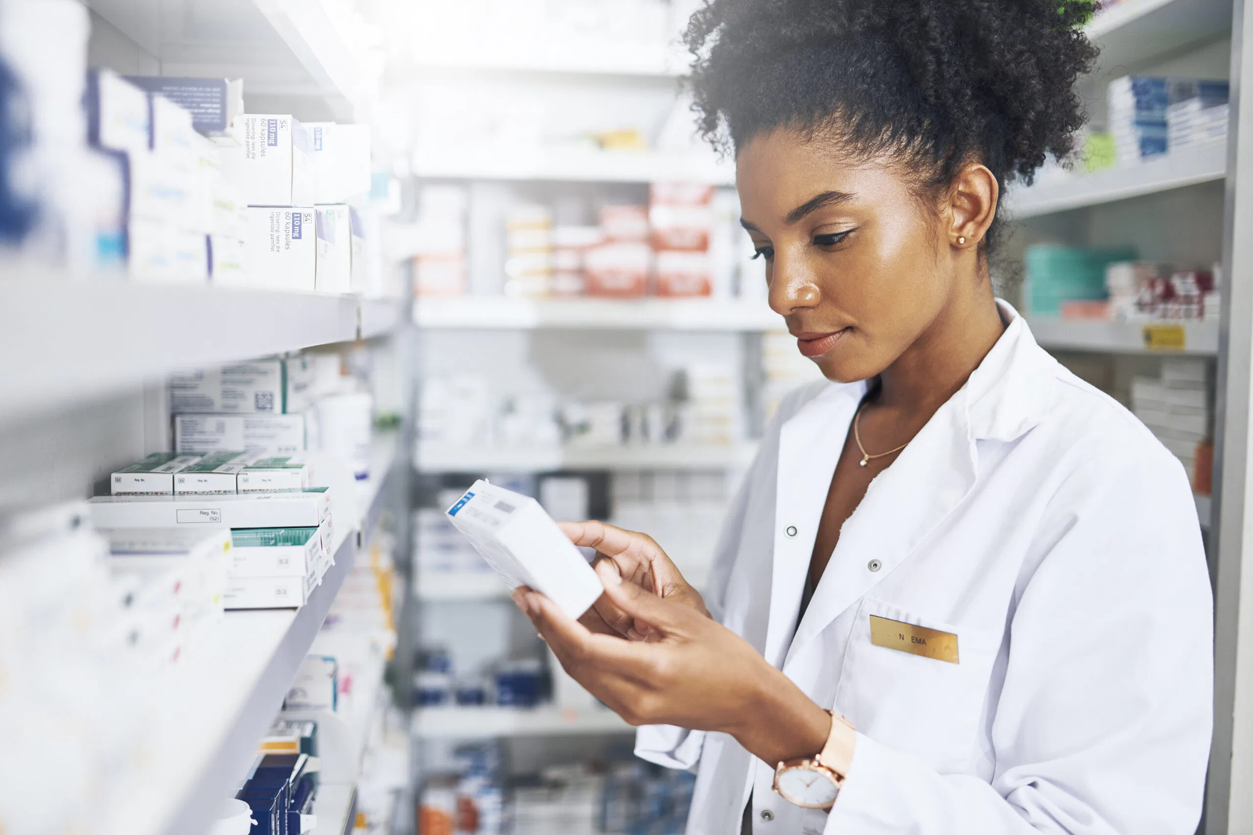 Black woman, pharmacist and medicine box in clinic for product stock, ingredients and check information on label. Female person, list and reading pills for medical inventory, inspection and retail