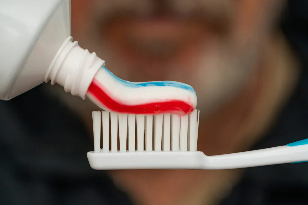 Squeezing colored toothpaste onto a toothbrush.